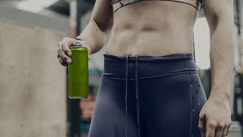 woman in gym showing abs holding supplement drink