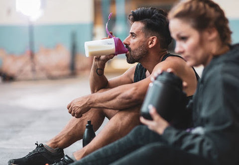 man and woman drinking pre workout supplements