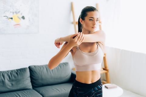 woman in living room stretching arms