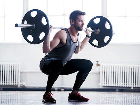 man doing squats lifting weights