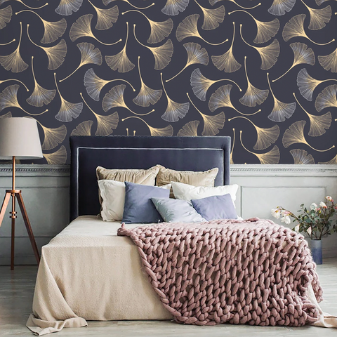 bedroom with gold and black gingko leaf wallpaper, lamp, throw blanket