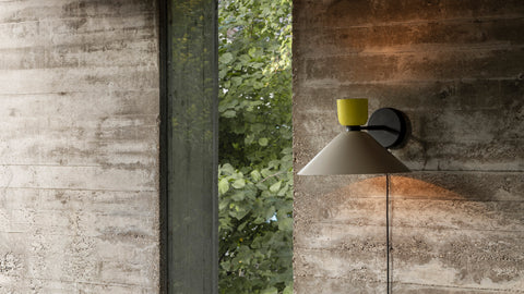 An Alphabeta Wall Light + Cable mounted to a stone wall.