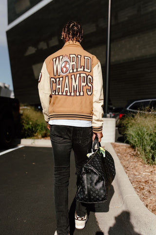 Minnesota Vikings Cornerback, Cameron Dantzler seen wearing the Homme Femme World Champs Letterman Jacket in camel brown. Cream leather contrast sleeves with brown ribbing at cuff and waistband. "HF" patches at front with embroidered "Maison De Homme Femme" at right lower front coincide with the raw racing aesthetic. "World Champs" embroidery at back. 5-button closure at front with 2-button closure at waistband. Welt pockets at front. (via Cameron Dantzler, @camdantzler3)