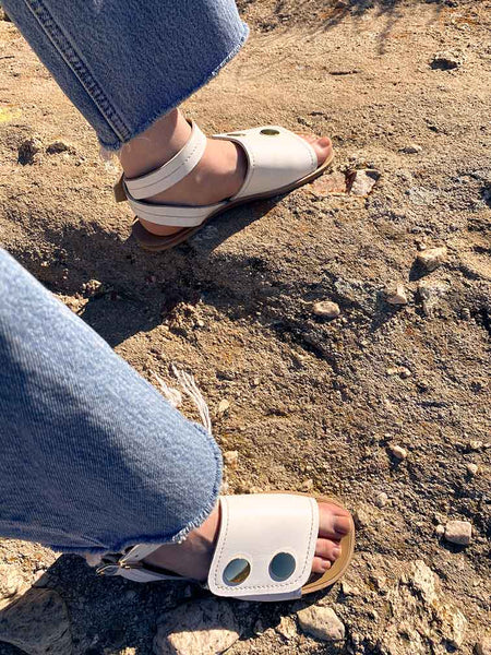 woman wearing frayed blue Levis jeans with open toe white leather sandals with fully covered vamp and ankle strap