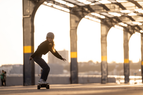 riding electric skateboard at sunset