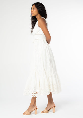 A side facing image of a black model wearing a white cotton eyelet maxi dress.