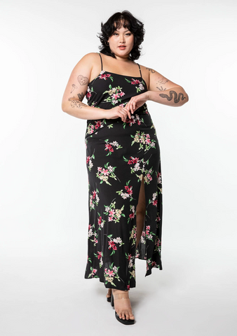 An extra large sized model wearing a nineties inspired black sleeveless maxi dress with an allover floral print.