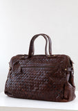 [Color: Brown] A luxurious brown woven leather bag. With two zippered compartments, a removable long leather crossbody strap, two leather top handles, and an exterior zippered pocket. 