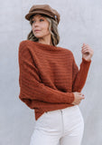 [Color: Burnt Orange] A blonde model wearing a fuzzy dark orange boatneck sweater. The wide neckline can be worn off the shoulder.  