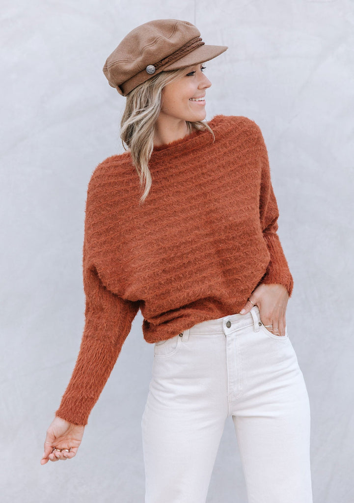 [Color: Burnt Orange] A blonde model wearing a fuzzy dark orange boatneck sweater. The wide neckline can be worn off the shoulder.  