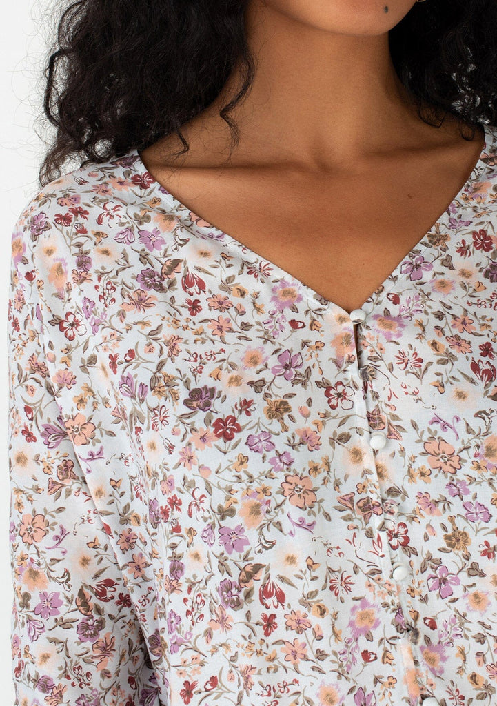 [Color: Mint/Rose] A close up front facing image of a brunette model wearing a casual bohemian top in a mint green and pink floral print. With three quarter length sleeves, a gathered sleeve detail with adjustable ties, a button front, and a v neckline. 