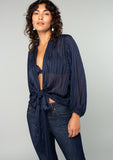 [Color: Navy] A front facing image of a brunette model wearing a sheer navy blue bohemian tie front top in a sparkly lurex stripe. With voluminous long sleeves and a tie front waist that can be styled in multiple ways. 