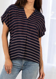 [Color: Navy/Blue] A model wearing a classic navy blue popover top in a gradient stripe print. Featuring a banded collar, short dolman sleeves with a folded cuff, and a sophisticated front pleat.
