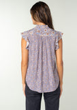 [Color: Grey/Natural] A back facing image of a brunette model wearing a best selling Helpone clickaway button front top in a grey and natural floral print. With short flutter sleeves and a ruffled neckline. 