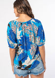 [Color: Turquoise/Black] A woman wearing a flowy bohemian top in a blue and black large floral print. With half length puff sleeves and a button front. 