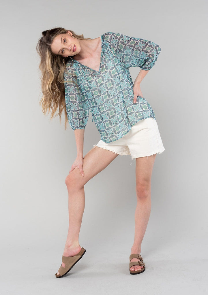 [Color: Cream/Navy] A full body front facing image of a blonde model wearing a sheer chiffon bohemian blouse in a blue floral geometric print. With three quarter length sleeves and a split neckline with ties. 