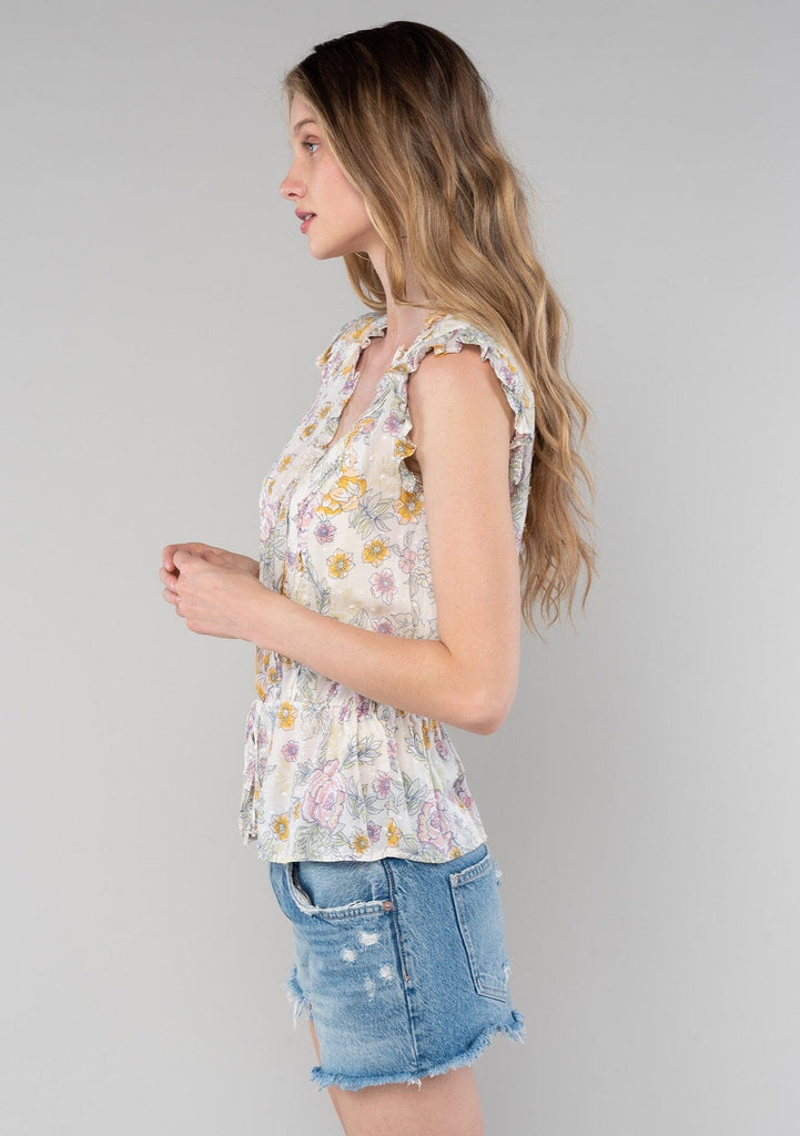 [Color: Natural/Pink] A side facing image of a blonde model wearing a lightweight bohemian spring peplum top in a pink floral print. With short ruffled sleeves, a ruffle trimmed v neckline, a self covered button front, and an adjustable drawstring waist with a tie. 