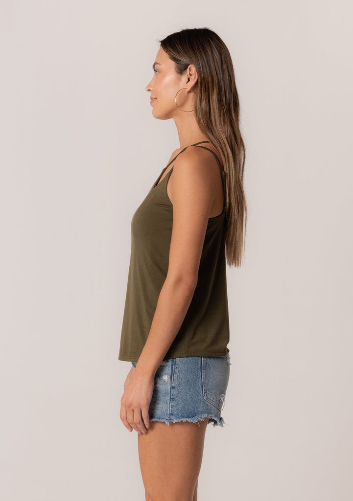 [Color: Military] A side facing image of a brunette model wearing a military green stretchy bamboo knit tank top with asymmetric spaghetti straps, a scoop neckline, and a relaxed slim fit.