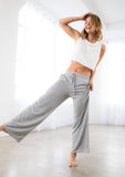 [Color: Light Heather Grey] A model wearing a soft knit wide palazzo leg pant. Featuring an elastic drawstring waistband and side pockets.