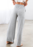 [Color: Light Heather Grey] A model wearing a soft knit wide palazzo leg pant. Featuring an elastic drawstring waistband and side pockets.