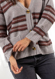 [Color: Grey/Raisin] A model wearing a grey stripe cardigan sweater. With three oversize buttons, front pockets, and a v neckline.