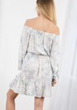 [Color: Lavender/Grey] A blond model wearing a tie dye mini dress. Featuring a smocked off the shoulder detail, an elastic waist, voluminous long sleeves, and a tiered ruffle trimmed skirt. 