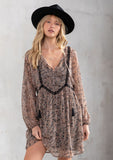 [Color: Black/Coral] A model wearing a dreamy sheer chiffon bohemian black and coral paisley mini dress. With contrast crochet trim, a baby doll dress silhouette, and long sleeves. A flowy Fall bohemian mini dress.