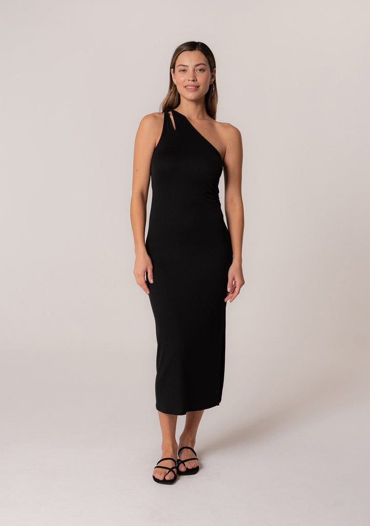 [Color: Black] A front facing image of a brunette model wearing a stretchy slim fit black knit midi dress with one shoulder strap, a cutout strap detail, and a side slit. 