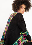 [Color: Black/Multi] A model wearing a black chunky knit cardigan with a multicolor shaggy yarn detail. Featuring a fringed waterfall hemline and an open front.