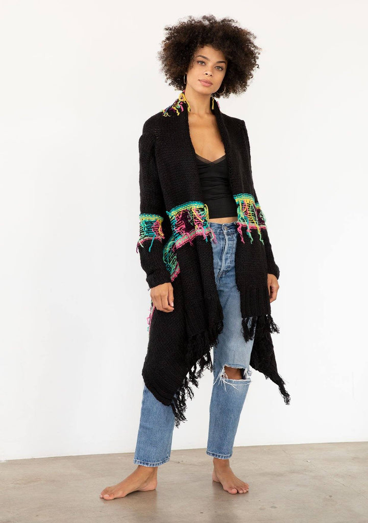 [Color: Black/Multi] A model wearing a black chunky knit cardigan with a multicolor shaggy yarn detail. Featuring a fringed waterfall hemline and an open front.