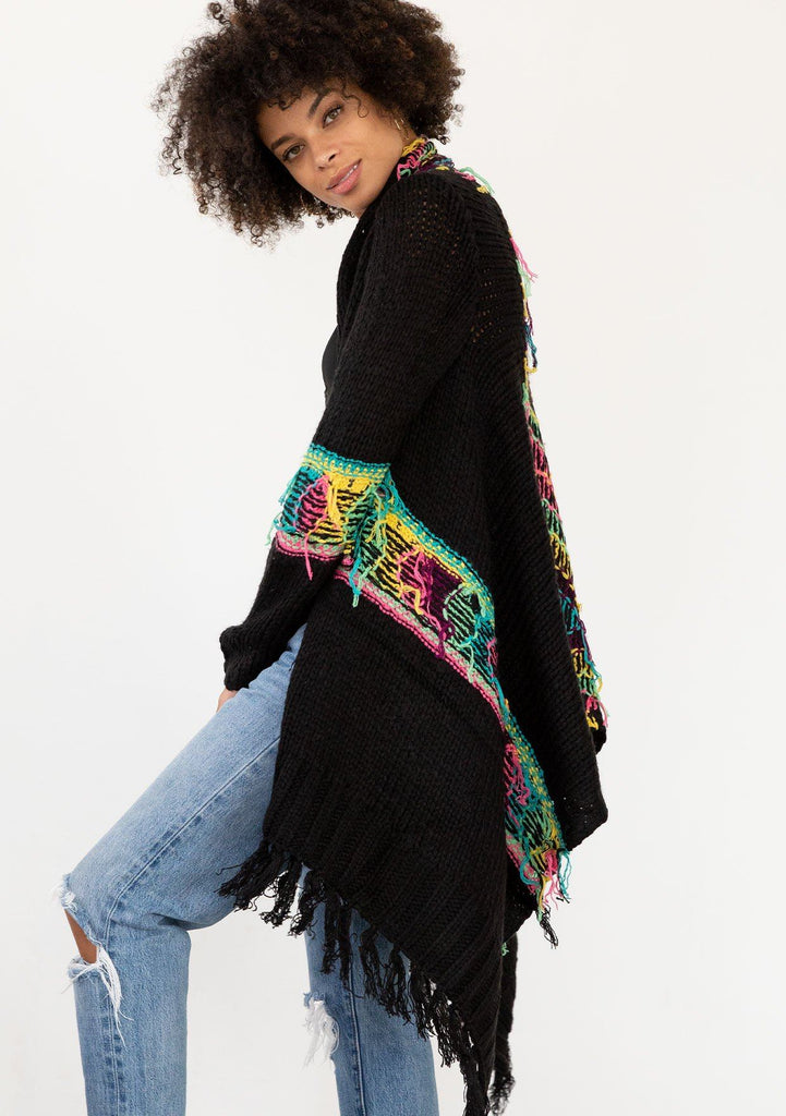 [Color: Black/Multi] A model wearing a black chunky knit cardigan with a multicolor shaggy yarn detail. Featuring a fringed waterfall hemline and an open front.