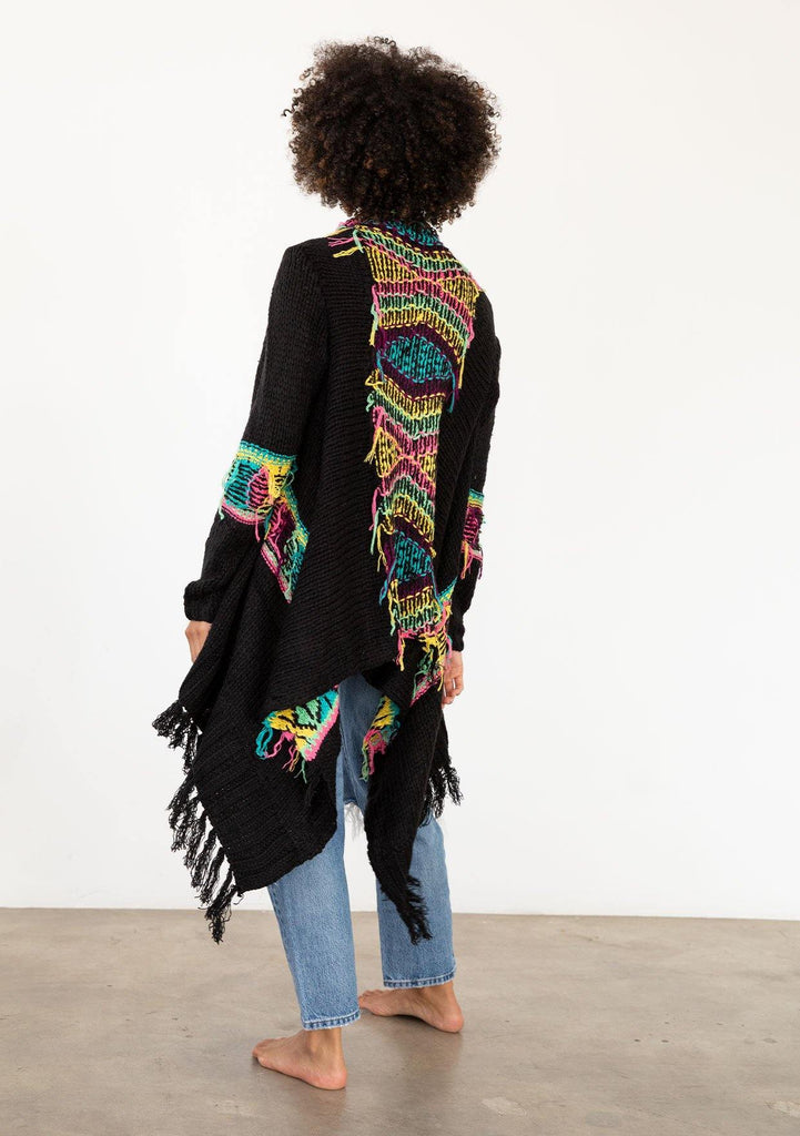 [Color: Black/Multi] A model wearing a black chunky knit cardigan with a multicolor shaggy yarn detail. Featuring a fringed waterfall hemline and an open front.