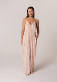 [Color: Natural/Peach] A front facing image of a brunette model wearing a best selling pink bohemian printed maxi dress. With adjustable spaghetti straps, a deep v neckline in the front and back, a flowy, oversize cocoon fit, and side pockets.