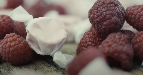 Old fashioned raspberry salt water taffy candy surrounded by raspberries