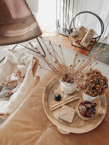 Smiling baby next to a beautifully arranged ottoman