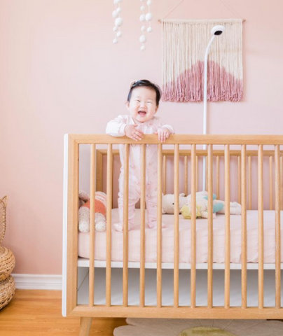 Nora in her crib in her soft pink nursery
