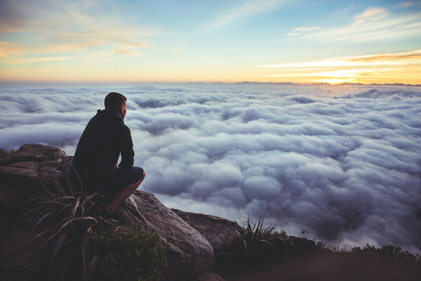 Man on top of mountain, above the clouds; peaceful reflection