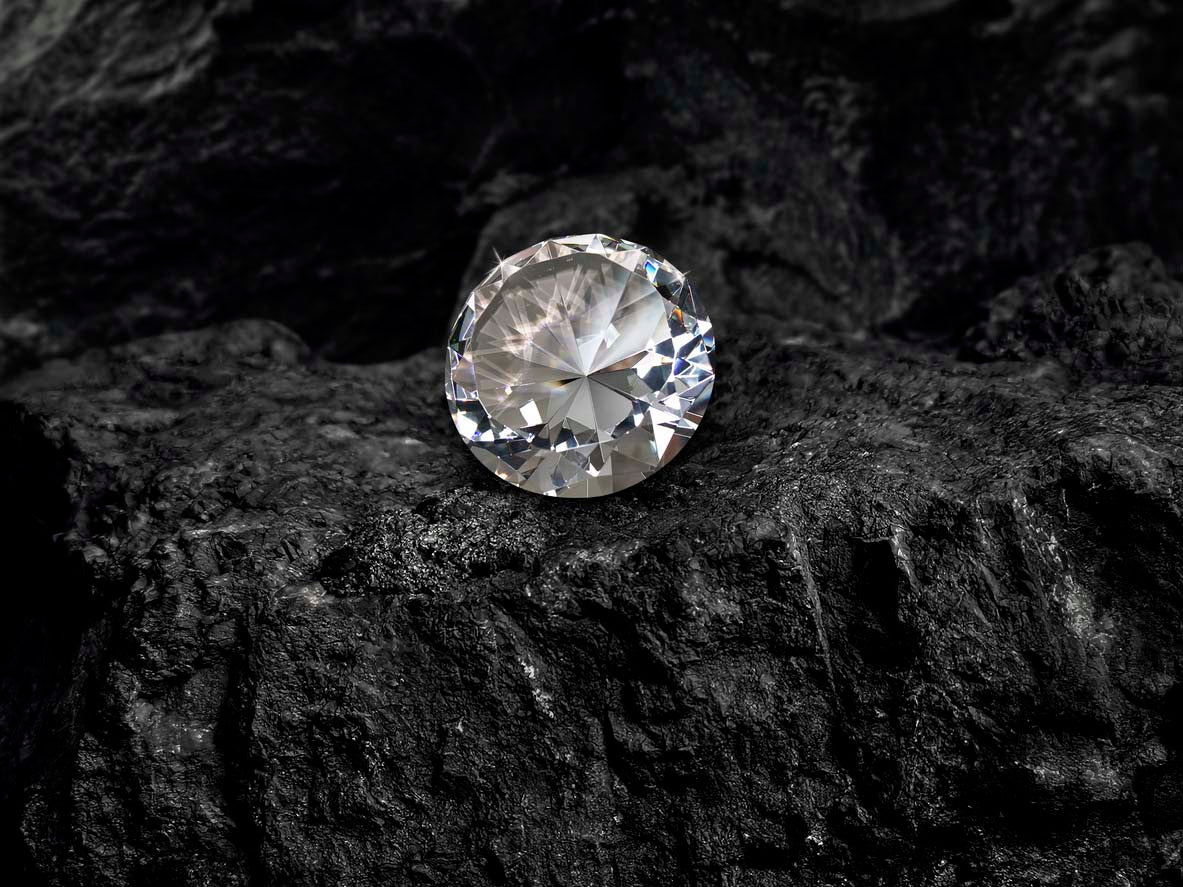 Loose diamond sitting on a black rock.