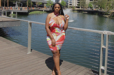 A young lady by the lake in an orange flower dress. 