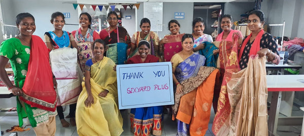 artisan women wearing saris smiling and holding a sign that says 'six yards plus thank you'