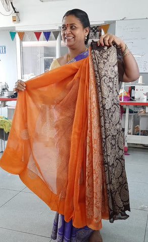 woman standing holding up sari and smiling