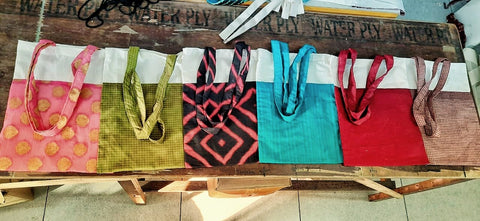 five upcycled sari and cotton tote bags laying flat on a wooden table