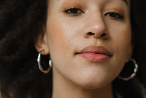  A woman looking at the camera wearing lovely silver hoop earrings.