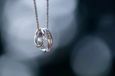 Two silver wedding rings hung together on a silver chain.