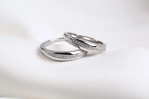 two platinum diamond rings sitting on each other on a white sheet