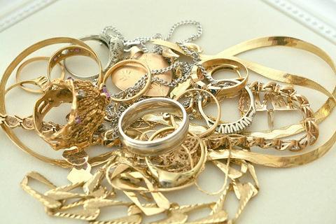 a pile of gold necklaces, earrings, and bracelets on a white table