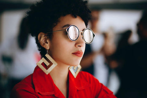 woman in sunglasses wearing geometric earrings