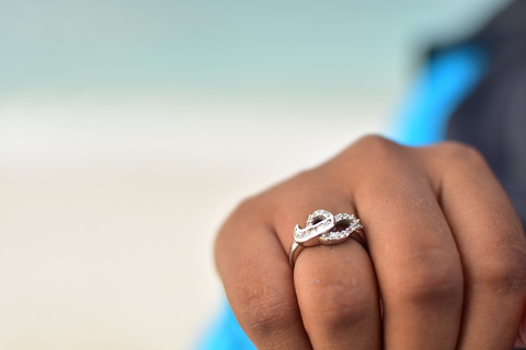  a hand with a diamond twist ring against a setting sky