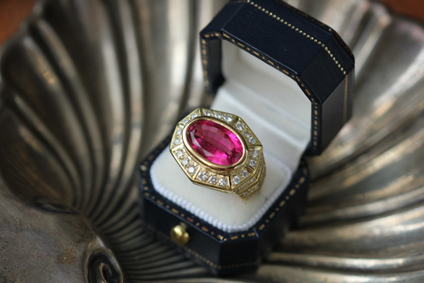  a pink stone set in a gold ring in a black ring box