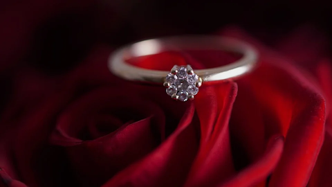 a gold ring with a diamond stud on a table covered in wine red sheets